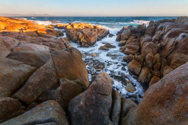Sahildeki suyun yanında kayalar ve güneş ışığı