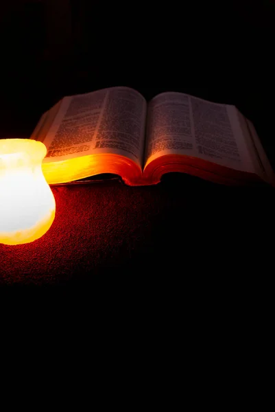 Otwórz Świętą Księgę Biblijną Oświetleniem Świecy Ciemnym Złotym Kolorze Kręgosłupa — Zdjęcie stockowe