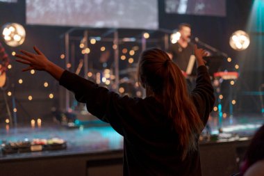 Canlı müzik konserindeki izleyiciler geceleri kollarını kaldırıp dans ediyorlar.