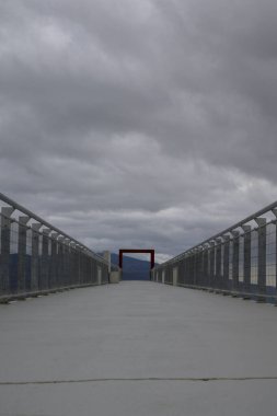 La Garganta, Extremadura 'daki modern, beton Deneysel Gözetleme Noktası' nın simetrik alçak açılı görüntüsü. Merkezi kırmızı çerçeve, ağır ve bulutlu bir gökyüzünün altındaki katmanlı dağ manzarasını vurgular.