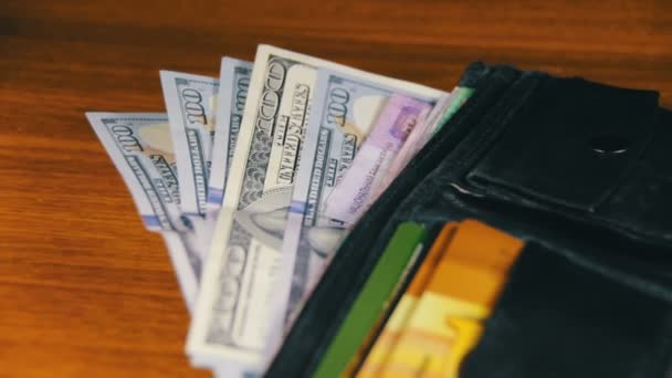 Гроші в гаманці обертаються на дерев'яному столі — стокове відео