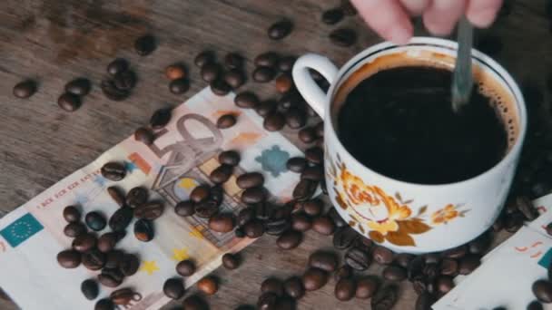 Koffiebonen, koffie Cup en Euro op een houten tafel — Stockvideo