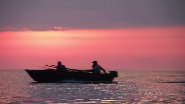 Човен на захід сонця тлі плаваючі на морі — стокове відео