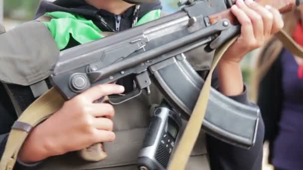 Der Teenager in einer Flakjacke mit einem Maschinengewehr in der Hand — Stockvideo