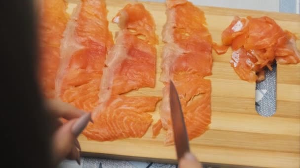 Jonge vrouwen snijdt zalm vlees in kleine stukken op snijplank thuis keuken — Stockvideo