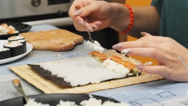 ホームキッチンで寿司を作る。少女の手で具材を海苔にかける — ストック動画