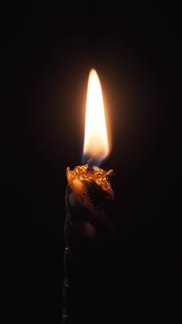 Vertikala bilder. En "Single Candle Lit" på svart bakgrund. Ljusflamma i mörker — Stockvideo