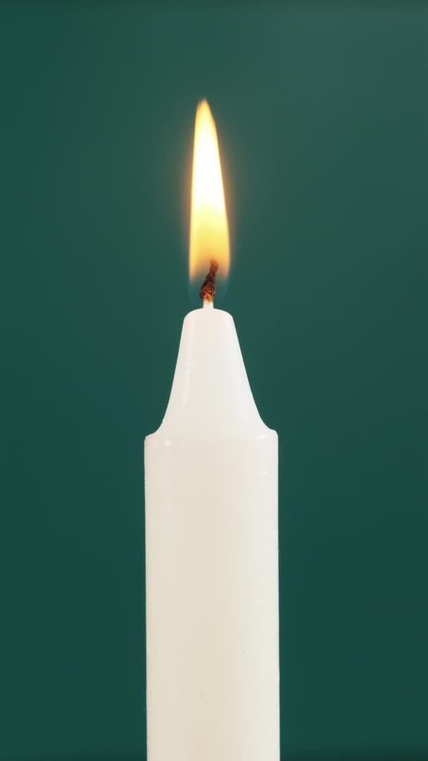 Una singola candela è accesa su sfondo verde. Illuminazione. Fiamma di candela — Video Stock