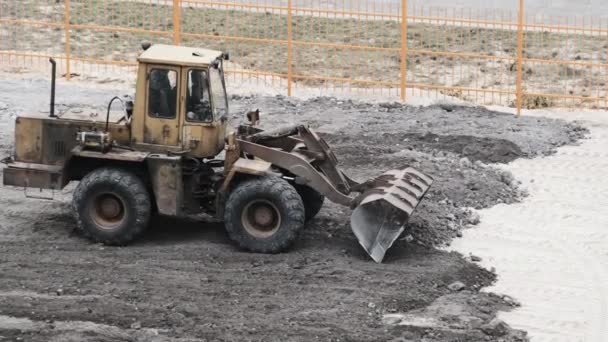 En gammal bulldozer på gummihjul fungerar på byggarbetsplatsen. — Stockvideo