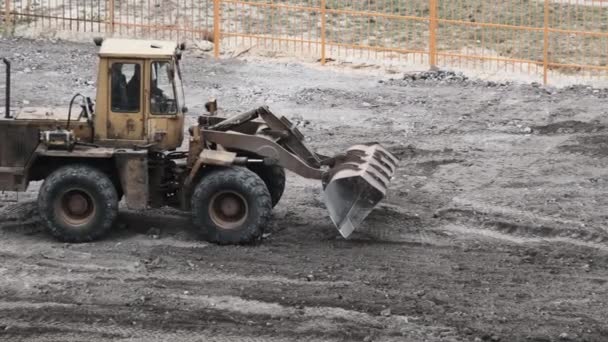 Eine alte Planierraupe auf Gummirädern arbeitet auf der Baustelle. — Stockvideo