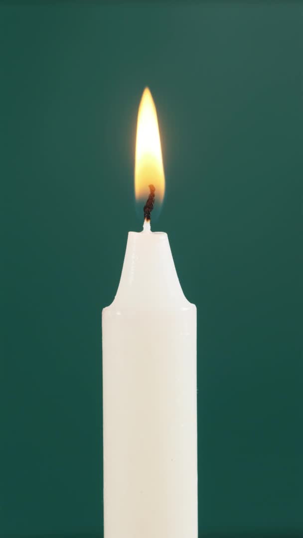 Single Candle is Lit op een groene achtergrond. Kaarsen uitblazen, roken — Stockvideo