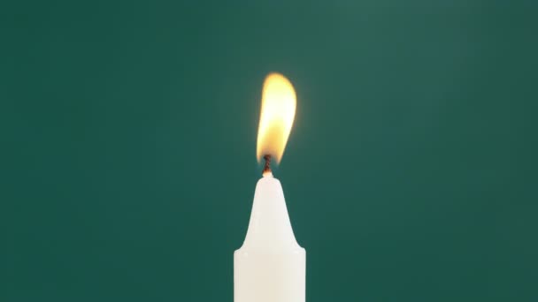 Jedna svíčka je Lit na zeleném pozadí. Osvětlení. Plamen svíčky — Stock video