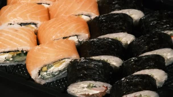 Sushi Rolls se otáčí v plastovém kontejneru na černém pozadí. Dodávka jídla — Stock video