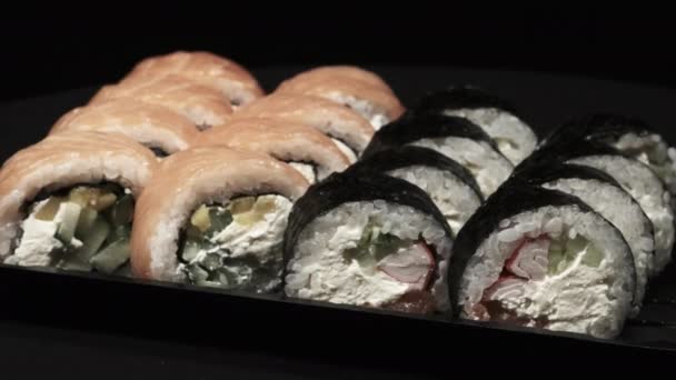 Los rollos de sushi giran en un contenedor de plástico sobre un fondo negro. Entrega de comidas — Vídeo de stock