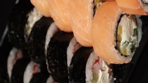 Vertical Video. Sushi Rolls se rotește într-un container din plastic pe un fundal negru — Videoclip de stoc