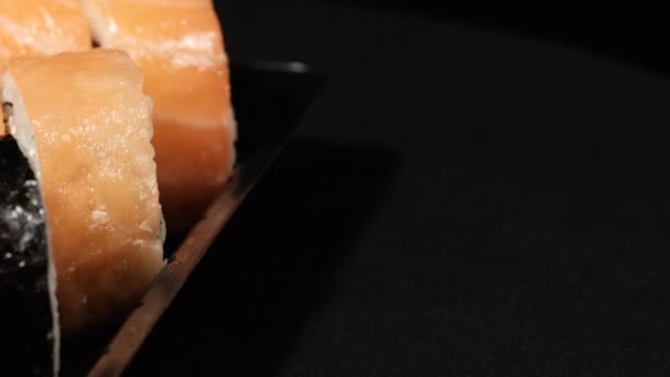Los rollos de sushi giran en un contenedor de plástico sobre un fondo negro. Entrega de comidas — Vídeo de stock