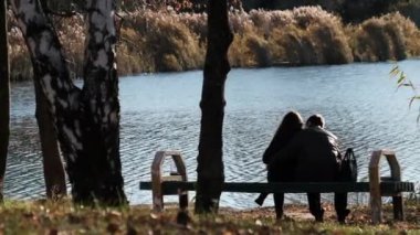 Genç Romantik Çift Nehir kenarındaki bir sonbahar parkında bir bankta oturuyor. Düş.