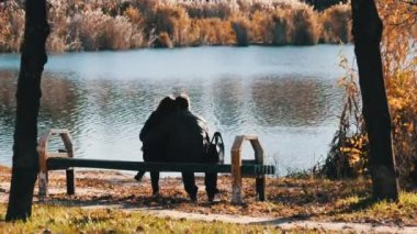 Genç Romantik Çift Nehir kenarındaki bir sonbahar parkında bir bankta oturuyor. Düş.