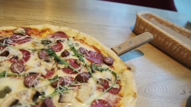 Świeżo przygotowana pizza na drewnianym stole w kawiarni. — Wideo stockowe