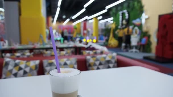 Copo de Latte está em uma mesa em um café dentro de um centro de entretenimento para crianças — Vídeo de Stock