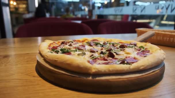 Свежеприготовленная пицца на деревянном столе в кафе. — стоковое видео