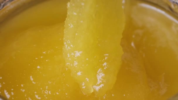 Miel Cristalina en un tarro. Primer plano extremo. La cuchara está sumergida en miel espesa — Vídeo de stock