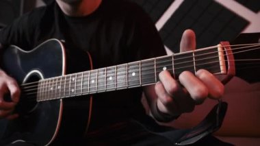 Evde Kayıt Stüdyosunda Kanepede otururken Akustik Gitar Çalan Genç Adam