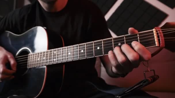 Ung mand spiller akustisk guitar, mens du sidder på Sofa i Home Recording Studio – Stock-video