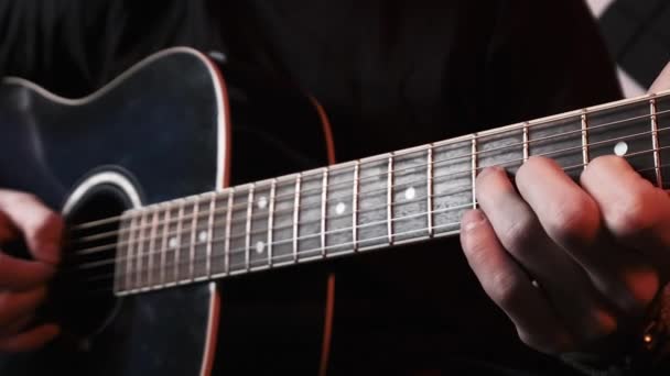 Młody człowiek gra na gitarze akustycznej siedząc na kanapie w studiu nagraniowym — Wideo stockowe