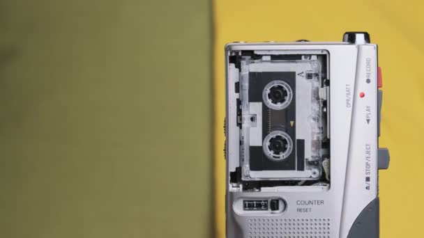 Портативный ретро-магнитофон с микрокассетным звуком на жёлтом фоне — стоковое видео