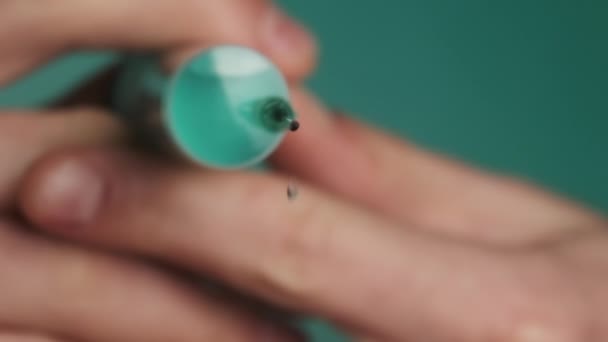 Aguja de jeringa con gotas líquidas de medicación en las manos del médico — Vídeo de stock