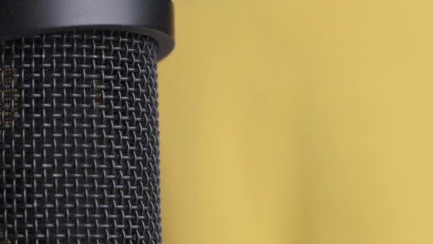 Microfone condensador de estúdio gira em fundo amarelo com lugar para texto — Vídeo de Stock