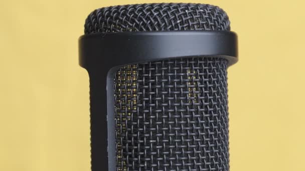 Microfone condensador de estúdio gira em fundo amarelo com lugar para texto — Vídeo de Stock