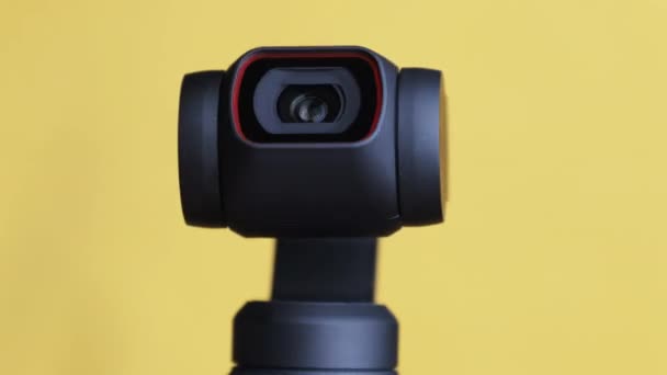 Объектив механической камеры Gimbal вращается на желтом фоне, макрос роботизированной камеры — стоковое видео