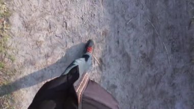 Kirli ve güneşli bir kış ormanı yolunda yürüyen bir adamın bacaklarının POV görüntüsü