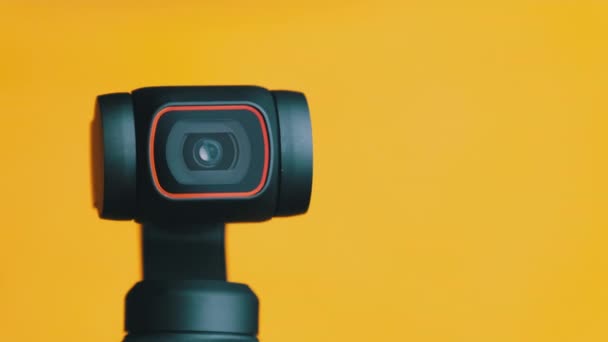 Lente de cámara Gimbal mecánica gira sobre fondo amarillo, cámara robótica Macro — Vídeo de stock