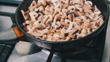 Mantarlar ev mutfağında bir tavada kızartılıyor, Julienne mantarları pişiriliyor.
