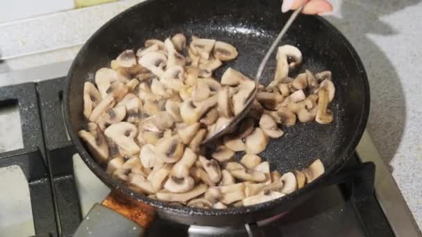 Женщины смешивают саутоидные грибы в кастрюле на домашней кухне, приготовление пищи Julienne — стоковое видео