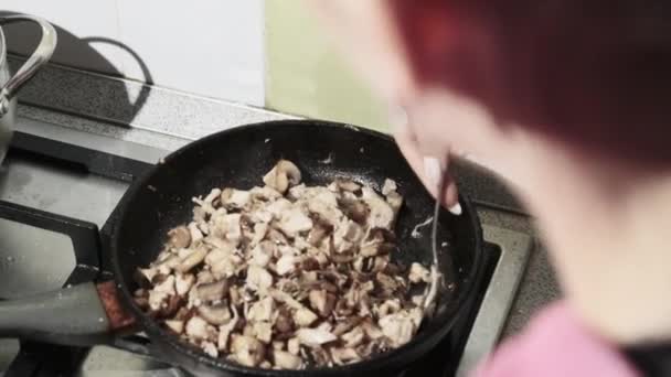 Mulher jovem preparando cogumelos fritos com queijo e carne na cozinha em casa — Vídeo de Stock