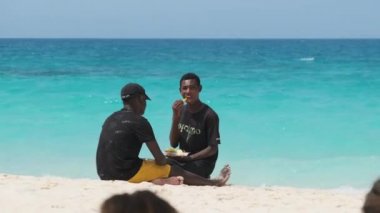 İki Afrikalı genç, Sunny Day, Zanzibar 'da Nakupenda sahilinde meyve yiyorlar.