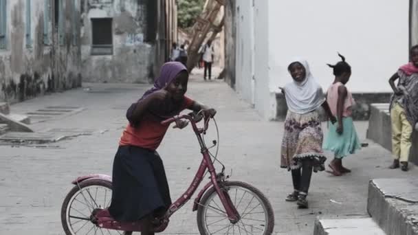 喜庆的骑自行车的可怜的非洲女孩微笑着，显露出丰满的标志，石城 — 图库视频影像