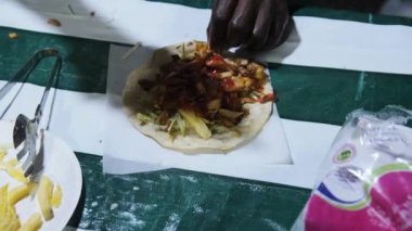 Bir satış şefi Stone Town gece pazarında bir Zanzibar shawarma hazırlıyor..