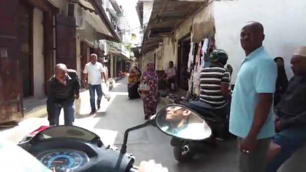 Езда на скутере по узким грязным улицам каменного города с бедными африканцами — стоковое видео