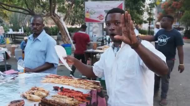 Продовольственные лавки Forodhani, африканский продавец рекламирует свой продовольственный рынок Занзибар — стоковое видео