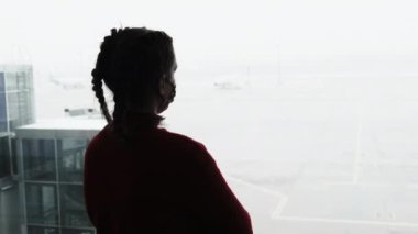 Havaalanı Terminalinde Uçağı izleyen Maskeli Genç Bir Kadının Silueti