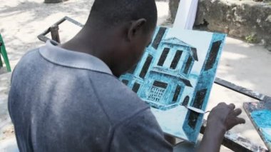 Bir sokak sanatçısı, Afrika 'da bir bankta yağlı boyalarla resim yapıyor..