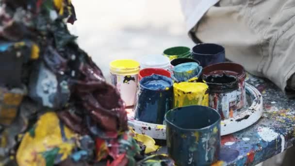 Uma paleta multicolorida de um artista pintando um quadro no parque em um banco — Vídeo de Stock