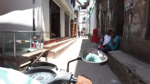 Monter une moto par étroites rues sales de Stone Town avec les pauvres Africains — Video