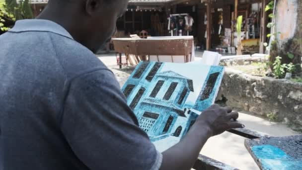 A street artist paints a picture with oil paints in the park on a bench in Africa. — Stock Video