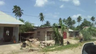 Palmiye ağaçları ve Afrika 'nın arasında harap olmuş evleri olan gecekondu ve köylerin önünden geçmek